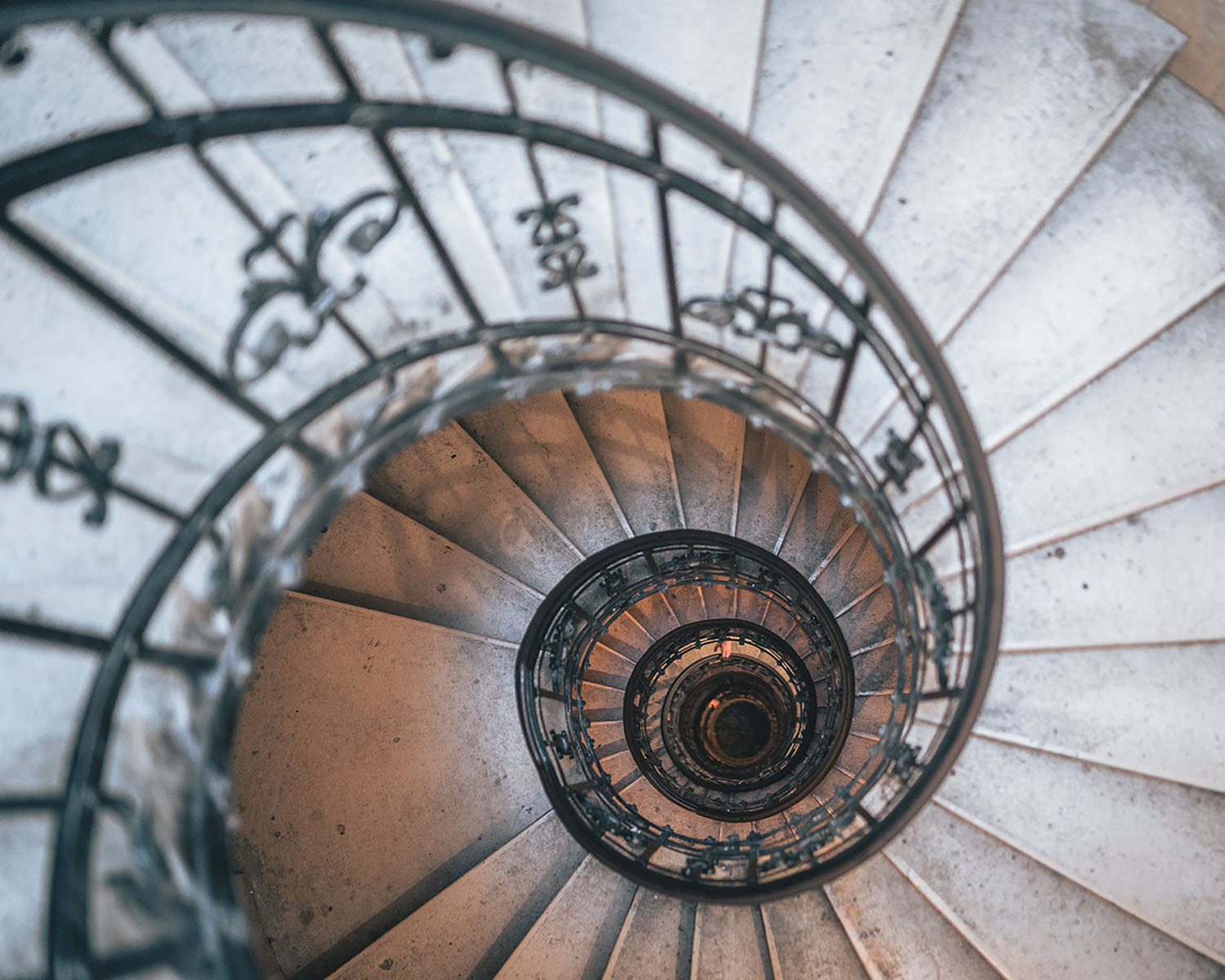 Escalera de caracol con barandal de hierro y detalles ornamentales.