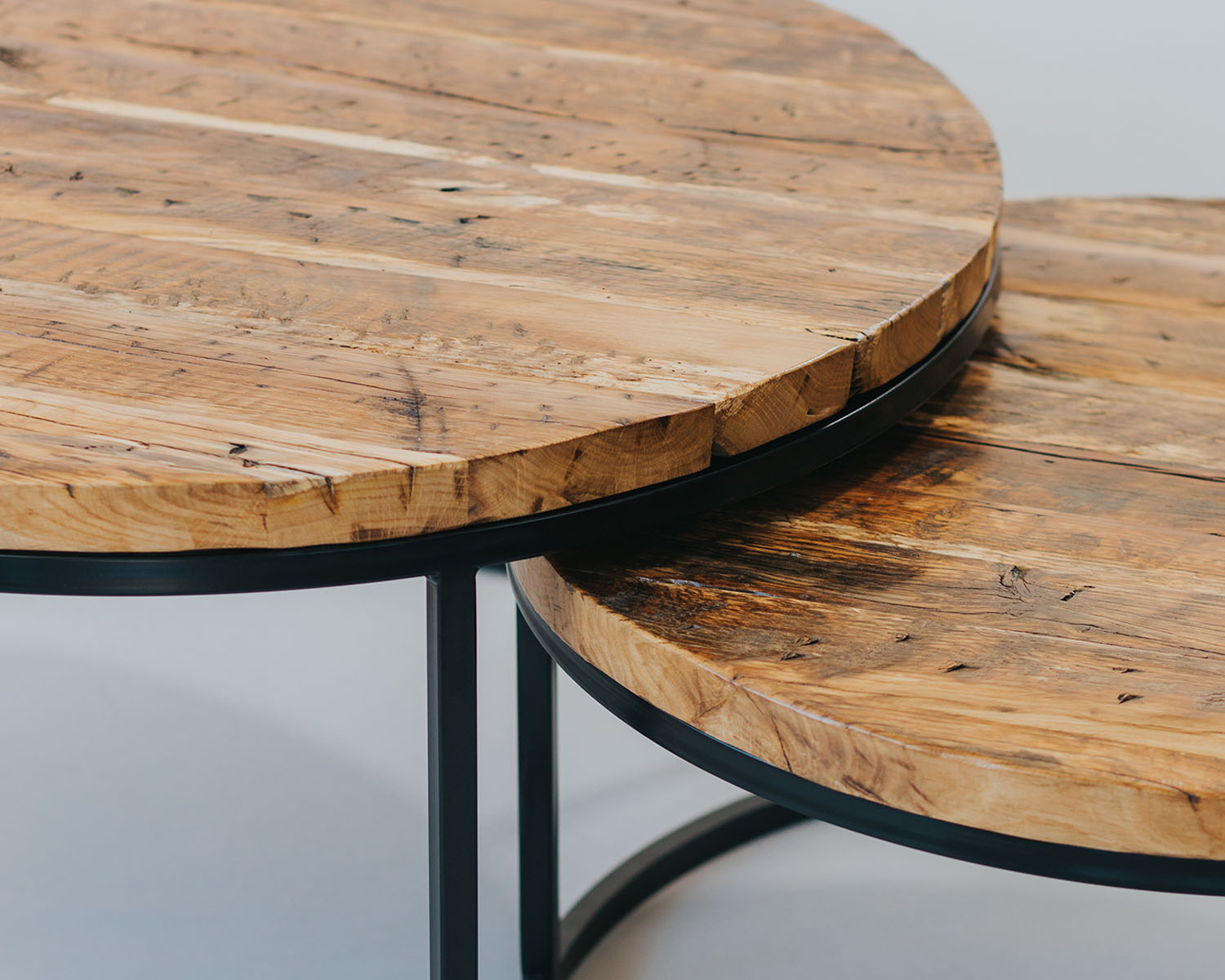 Mesas redondas de madera con bases de hierro negro.