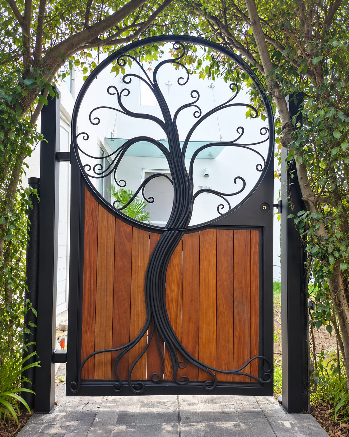 Portón de herrería con ramas de árbol forjadas y paneles de madera realizado por Mendieta
